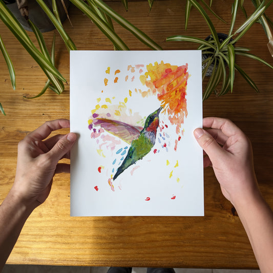 a person holding a piece of paper with a painting of a hummingbird on it